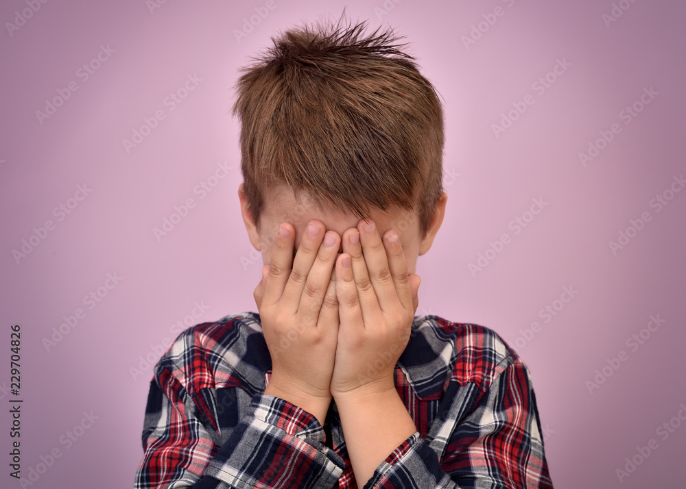 Scared young boy with hands on his face