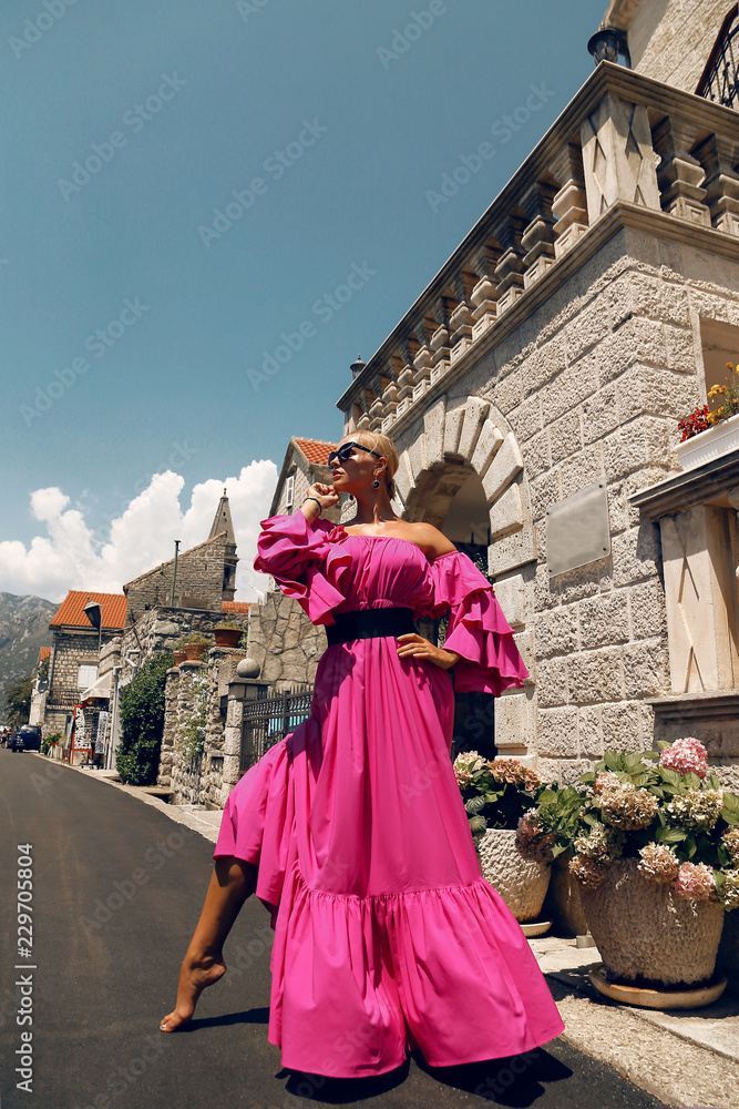Naklejka premium woman with blond hair in luxurious pink dress, having summer vacation in Europe