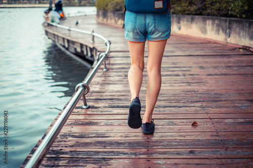 Close up foot. Girl is walking on the street Wood bridge riverside in the public park.