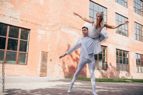 low angle view of young ballet dancers in white clothes dancing on urban city street