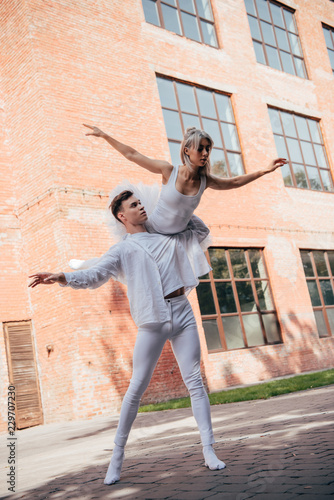 low angle view of young ballet dancers in white clothes dancing on street
