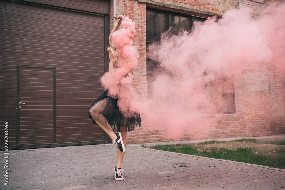 Fototapeta premium młoda kobieta współczesna tancerka w różowy dym na ulicy