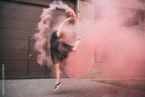 Fototapeta atrakcyjna młoda kobieta tańczy w różowy dym na ulicy