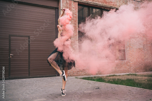 Fototapeta young female contemporary dancer in pink smoke on street