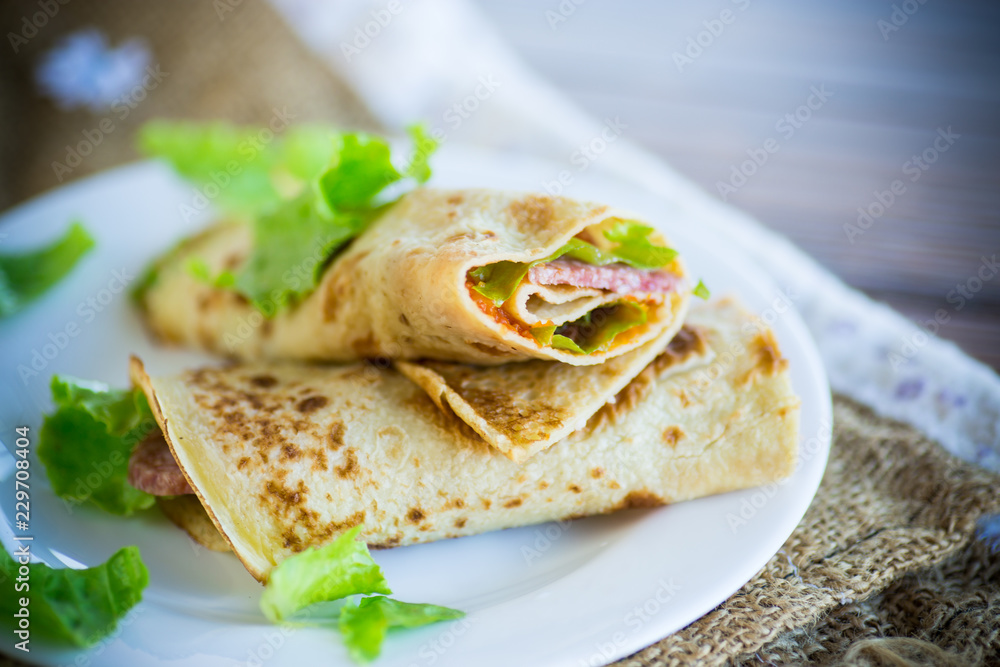 thin pancakes with salad leaves and bacon in a plate