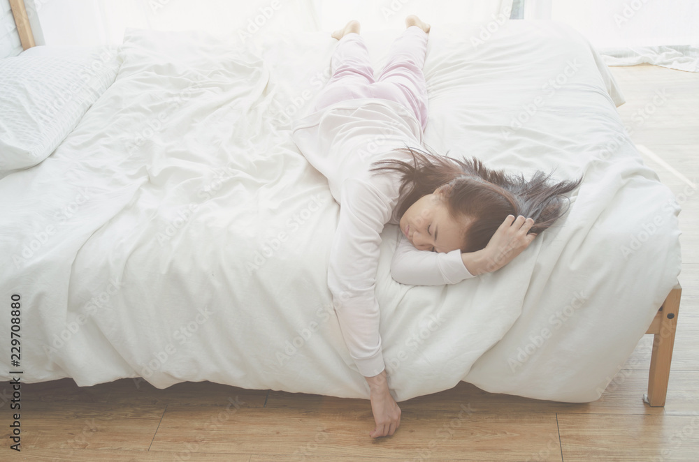 Beautiful woman sleeping in the bedroom. Woman lying face down on the bed.He slept with sleep.A woman wearing a pajama sleep sleeping on a bed in a white room in the morning.Warm tone. Beautiful woman sleeping in the bedroom. Woman lying face down on the bed.He slept with sleep.A woman wearing a pajama sleep sleeping on a bed in a white room in the morning.Warm tone.