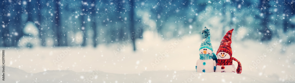 little knitted snowmans on soft snow on blue background - obrazy, fototapety, plakaty 