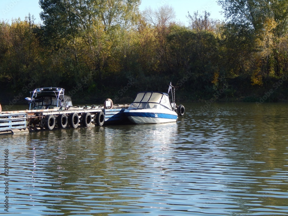 Fototapeta premium Motorboat on the pier. Boat on the lake near the pontoons in the fall. A photo.