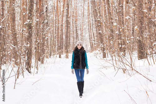 Happy young woman walking in winter time. Pretty girl in snowy nature