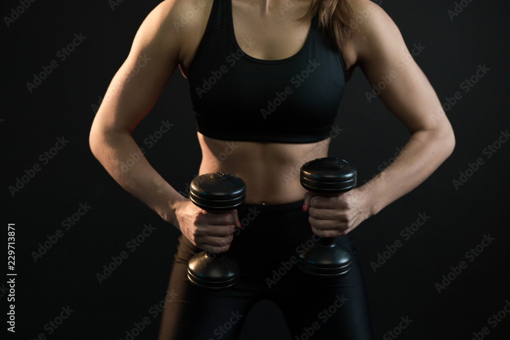 beautiful young girl goes in for sports with dumbbells on a black background beautiful young girl goes in for sports with dumbbells on a black background