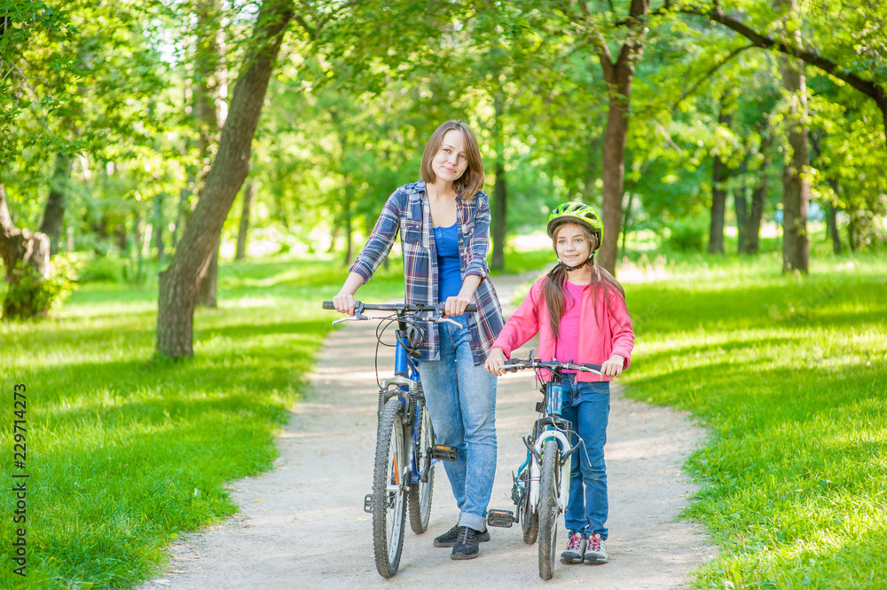 Mom and daughter are cycling in the park together Mom and daughter are cycling in the park together