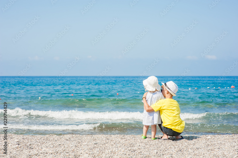 Young boy hugging baby girl on the beach on summer holidays. concept of summer family vacation. Empty space for text