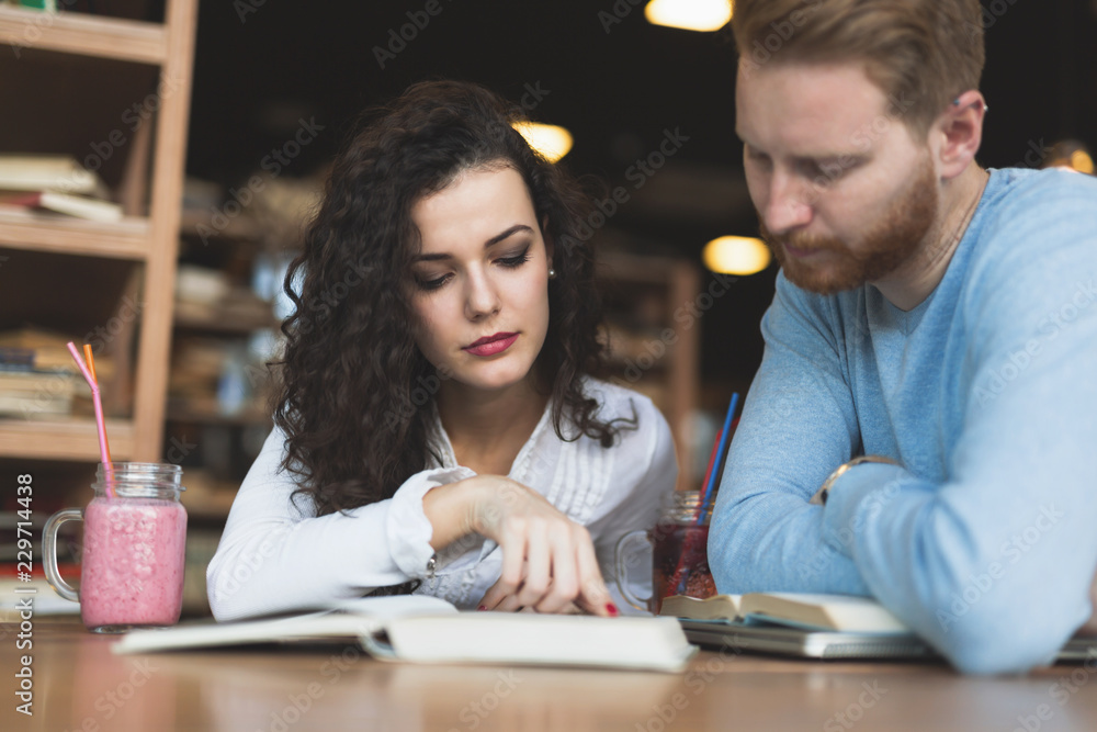 Young students spending time in coffee shop reading books