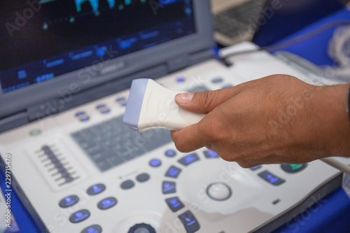 Ultrasound scanner in doctor hand for medical diagnostics with computer equipment