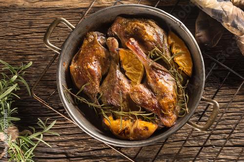 Roasted duck legs in pan with oranges herbs red cabbage and potato pankaces photo