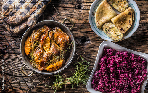 Roasted duck legs in pan with oranges herbs red cabbage and potato pankaces photo