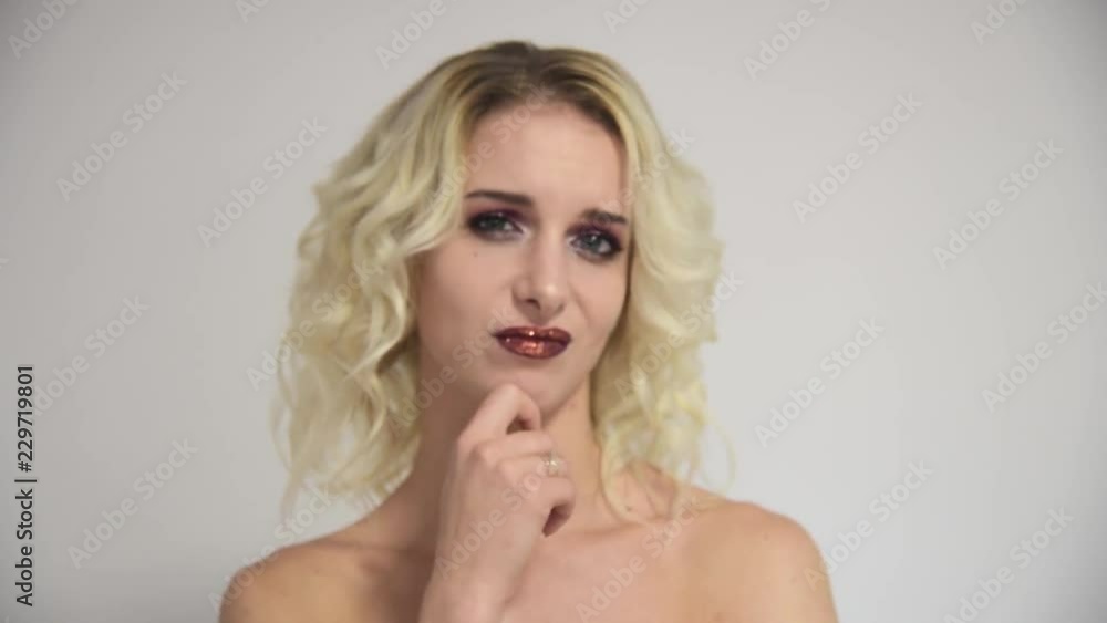 Beautiful blond beauty girl with perfect makeup on a white background shows emotions. Beauty style model is right in front of the camera and looks happy. Beautiful blond beauty girl with perfect makeup on a white background shows emotions. Beauty style model is right in front of the camera and looks happy.