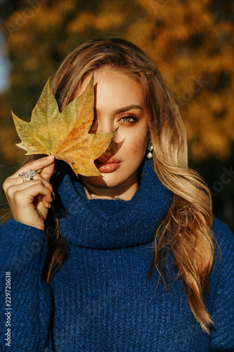 beautiful woman with blond hair in elegant outfit posing in autumn park