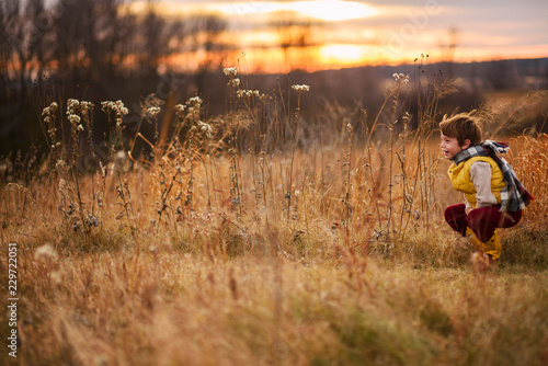 Smiling boy crouching in a field, United states photo