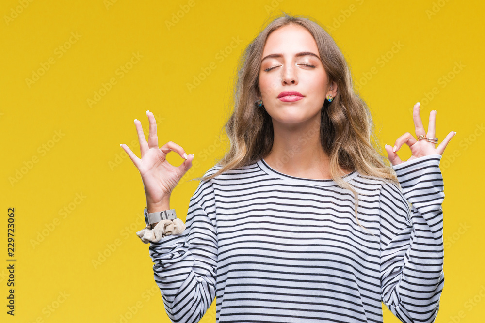 Beautiful young blonde woman wearing stripes sweater over isolated background relax and smiling with eyes closed doing meditation gesture with fingers. Yoga concept.