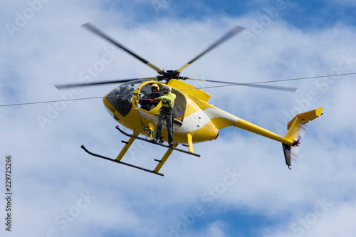 Helicopter crew working power lines blue sky clouds 