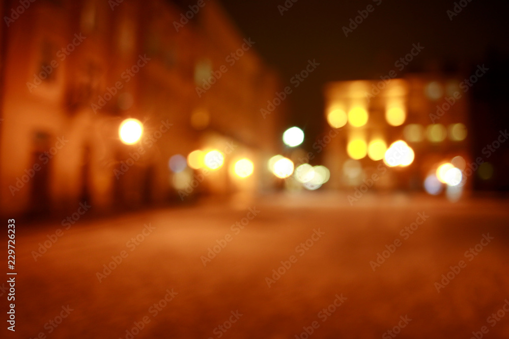 Blurred bokeh background of town square at night with people in light