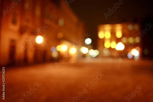 Blurred bokeh background of town square at night with people in light