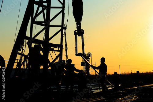 The oil workers are working in the sunset silhouettes
