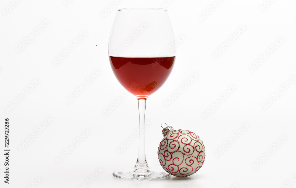 Wineglass with red liquid or wine and christmas ball ornament isolated on white background. Winter holidays concept. Glass with wine and christmas decoration. Winter celebration with alcohol drink Wineglass with red liquid or wine and christmas ball ornament isolated on white background. Winter holidays concept. Glass with wine and christmas decoration. Winter celebration with alcohol drink