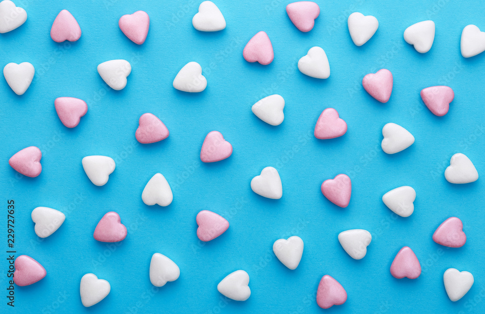 Heart shaped candies pattern on a blue background. Top view