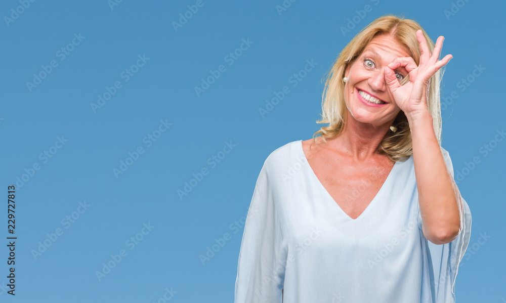 Middle age blonde business woman over isolated background doing ok gesture with hand smiling, eye looking through fingers with happy face. Middle age blonde business woman over isolated background doing ok gesture with hand smiling, eye looking through fingers with happy face.