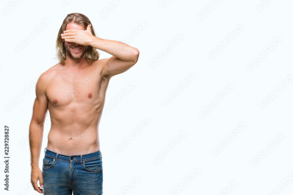 Young handsome shirtless man with long hair showing sexy body over isolated background smiling and laughing with hand on face covering eyes for surprise. Blind concept.