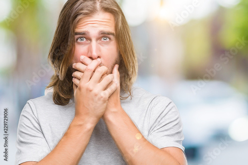 Young handsome man with long hair over isolated background shocked covering mouth with hands for mistake. Secret concept.