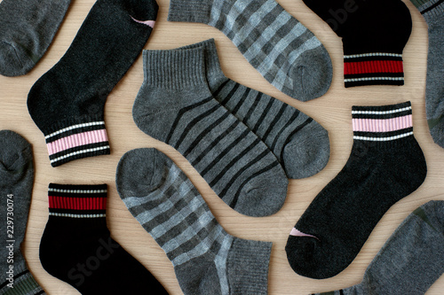 Set of gray and black socks. View from above. Warm clothing in the form of socks on a wooden background. Checkered and striped socks for fall and winter.