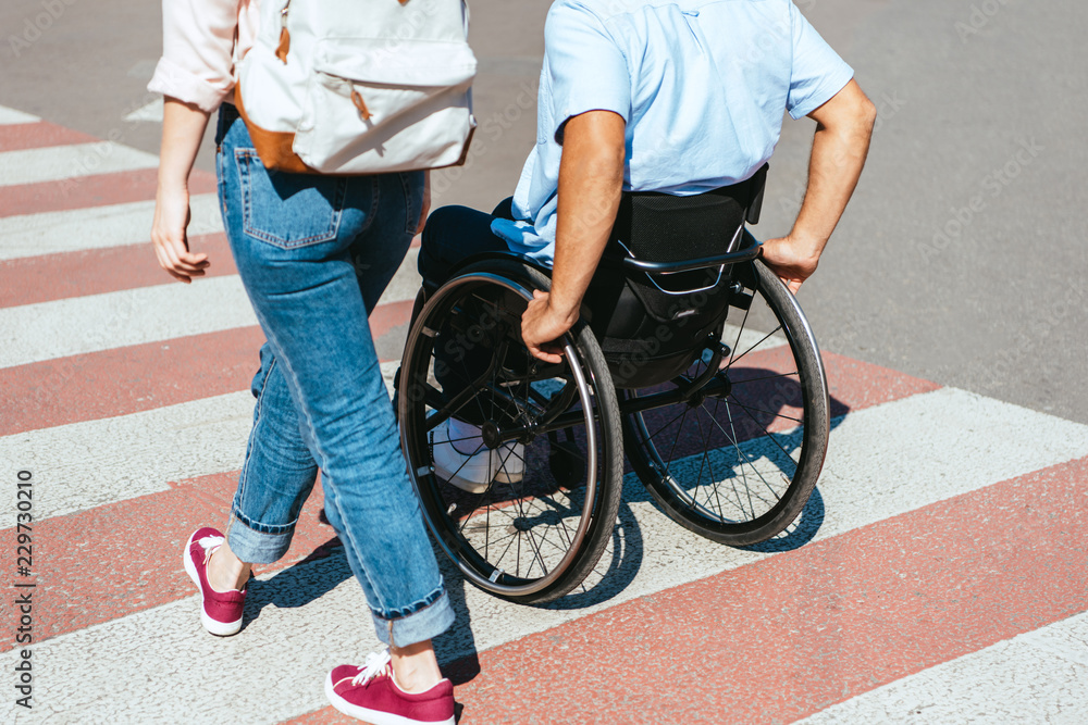Φωτογραφία cropped image of disabled boyfriend in wheelchair and girlfriend crossing crossw