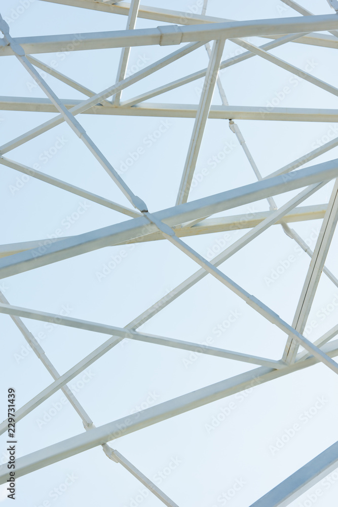 metallic parts of observation wheel construction against blue sky in amusement park