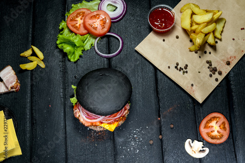  black burger on charred board with ingredients photo