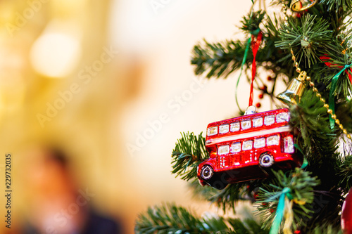 Fir tree decorated with toy double decker bus and light bulbs for Christmas and New Year celebration.