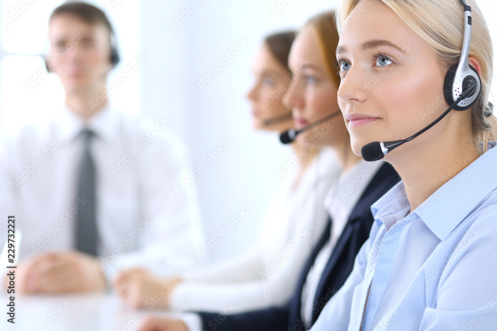 Call center. Group of operators at work. Focus at brunette business woman in headset Call center. Group of operators at work. Focus at brunette business woman in headset