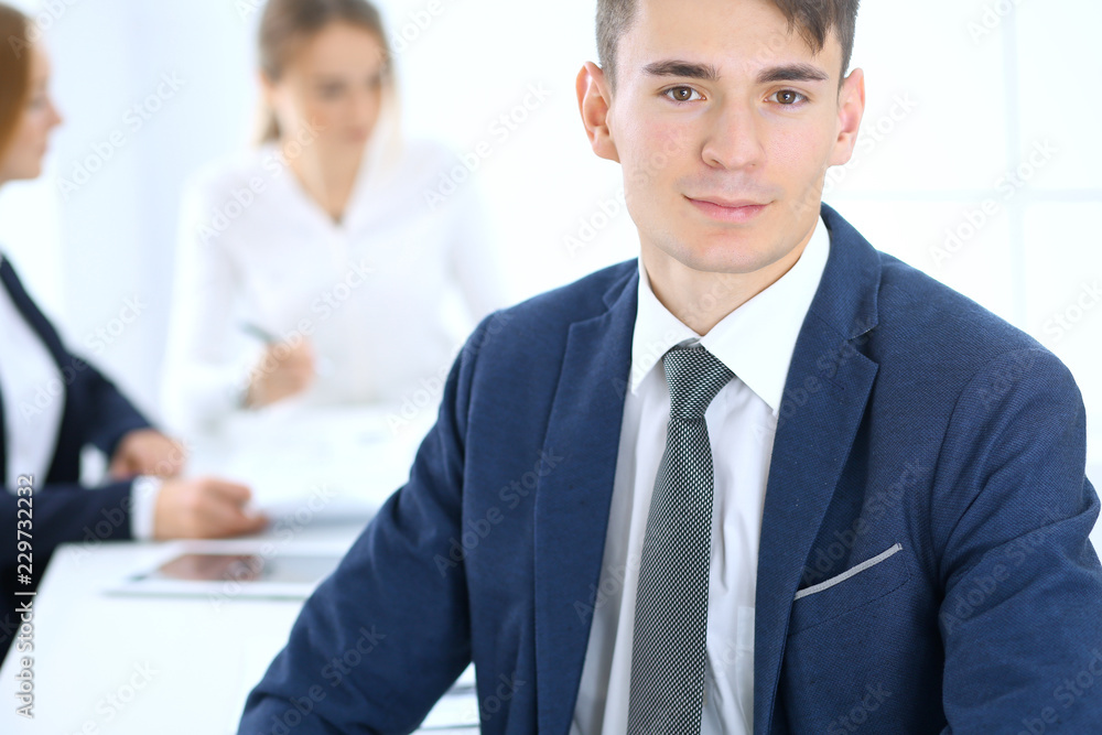 Group of business people or lawyers discussing terms of transaction in office. Focus at young businessman. Meeting and teamwork concept Group of business people or lawyers discussing terms of transaction in office. Focus at young businessman. Meeting and teamwork concept