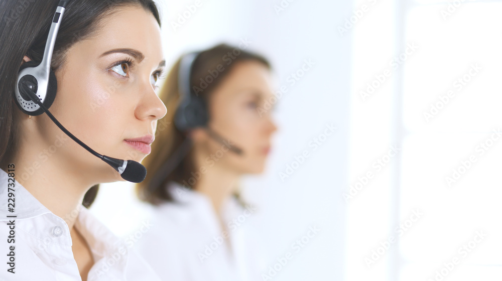 Group of call center operators at work. Focus on beautiful business woman in headset Group of call center operators at work. Focus on beautiful business woman in headset
