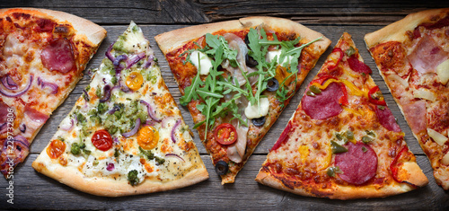 Photo Pieces of pizza of different various types on old retro boards banner concept