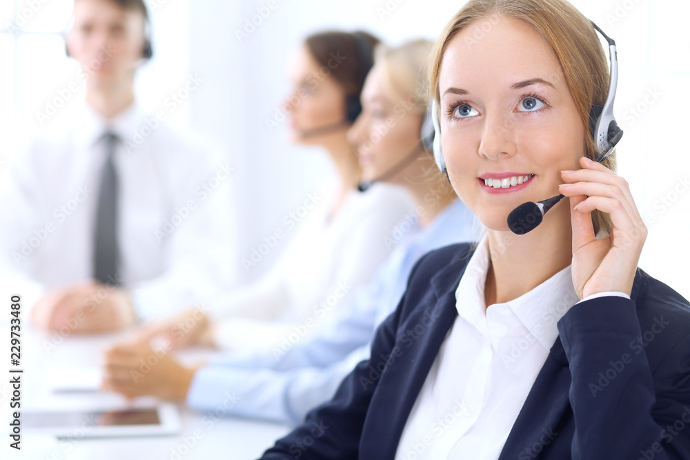 Call center. Group of operators at work. Focus at brunette business woman in headset Call center. Group of operators at work. Focus at brunette business woman in headset