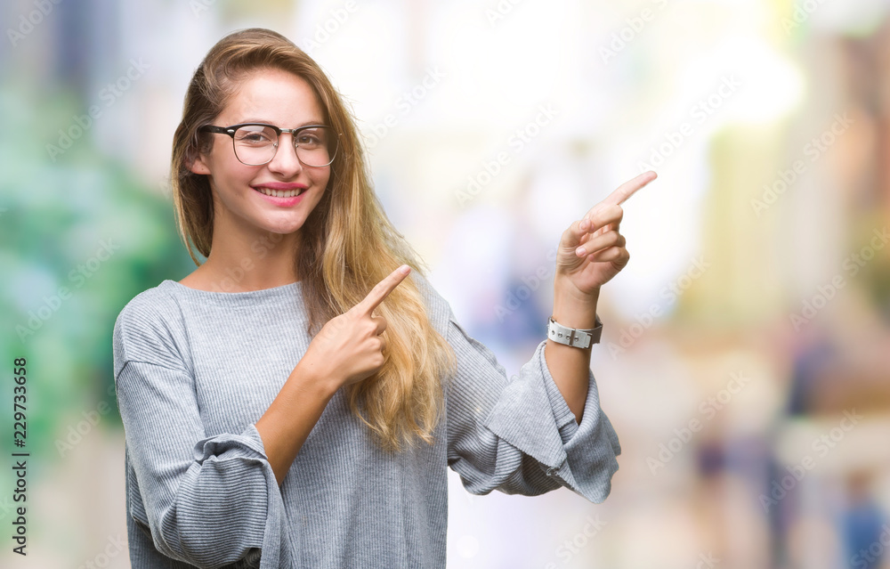 Young beautiful blonde woman wearing glasses over isolated background smiling and looking at the camera pointing with two hands and fingers to the side.