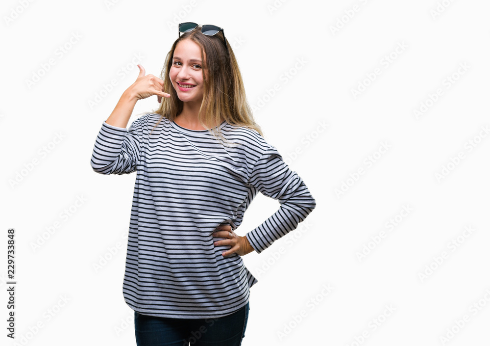 Young beautiful blonde woman wearing sunglasses over isolated background smiling doing phone gesture with hand and fingers like talking on the telephone. Communicating concepts. Young beautiful blonde woman wearing sunglasses over isolated background smiling doing phone gesture with hand and fingers like talking on the telephone. Communicating concepts.
