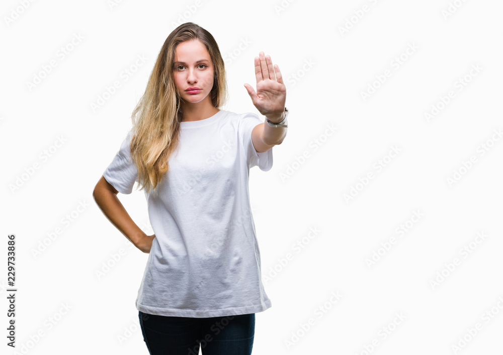 Young beautiful blonde woman wearing casual white t-shirt over isolated background doing stop sing with palm of the hand. Warning expression with negative and serious gesture on the face. Young beautiful blonde woman wearing casual white t-shirt over isolated background doing stop sing with palm of the hand. Warning expression with negative and serious gesture on the face.