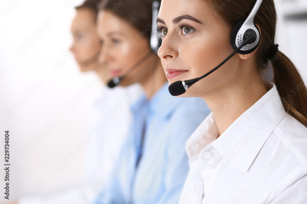 Call center. Group of operators at work. Focus on beautiful business woman in headset Call center. Group of operators at work. Focus on beautiful business woman in headset