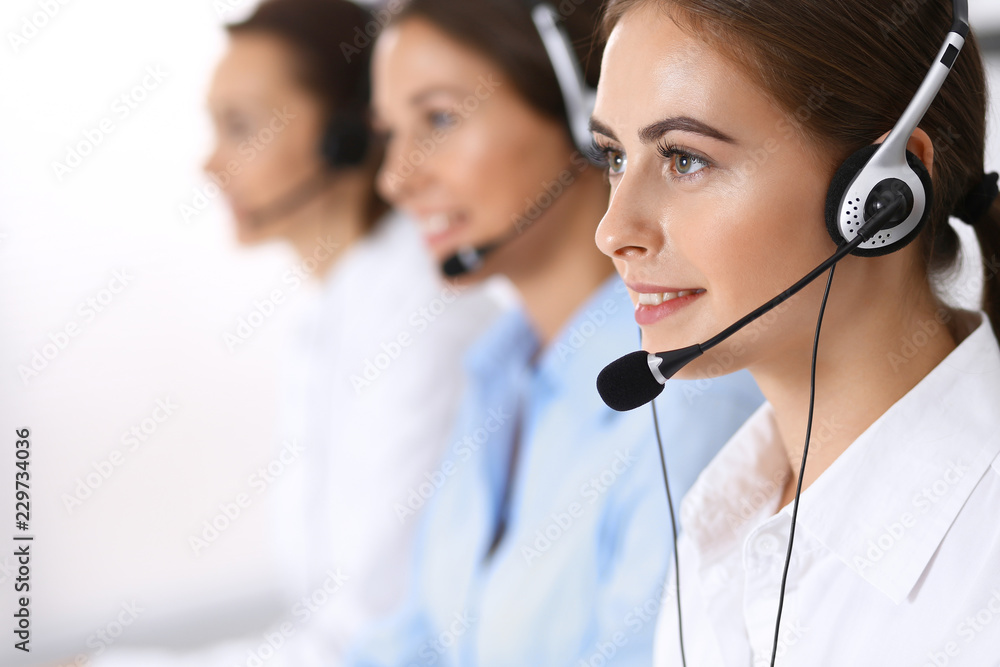 Call center. Group of operators at work. Focus on beautiful business woman in headset Call center. Group of operators at work. Focus on beautiful business woman in headset