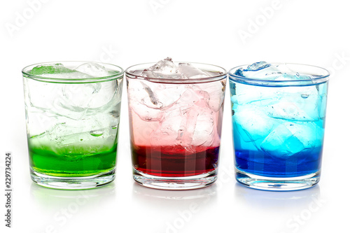 green, blue and red drink with ice cubes on white background