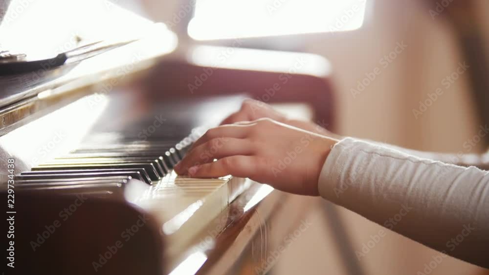 Child opening and playing piano. Close up on piano keys, child hands and fingers. Child opening and playing piano. Close up on piano keys, child hands and fingers.